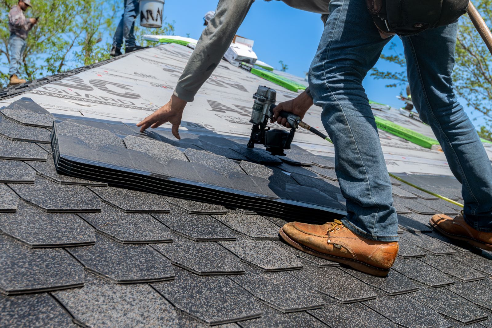 Roofer nailing asphalt shingles on a residential roof